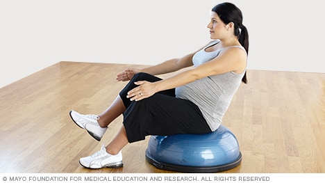 在平衡训练器上练习单腿 V 型坐姿的孕妇