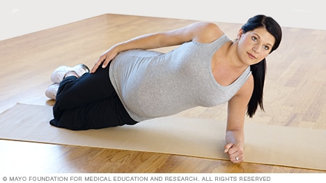 امرأة حامل تمارس نسخة معدلة من التمرين اللوحي (بلانك) الجانبي