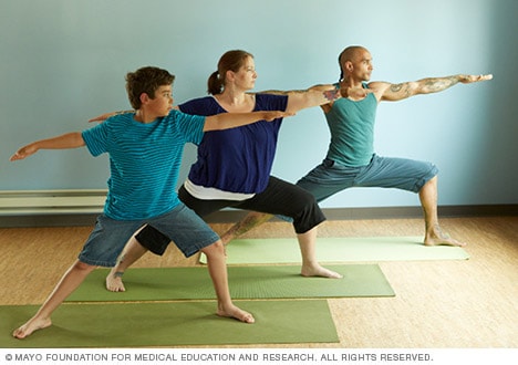 Group of Asian young people doing Yoga Poses for Beginners : Revolved  Standing Hand to Toe (Parivṛtta Hasta Pādāṅguṣṭhāsana). The trainer stand  in front of her student. Stand on Yoga mat in