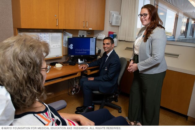 A Mayo Clinic doctor, new staff person and patient converse in an office.