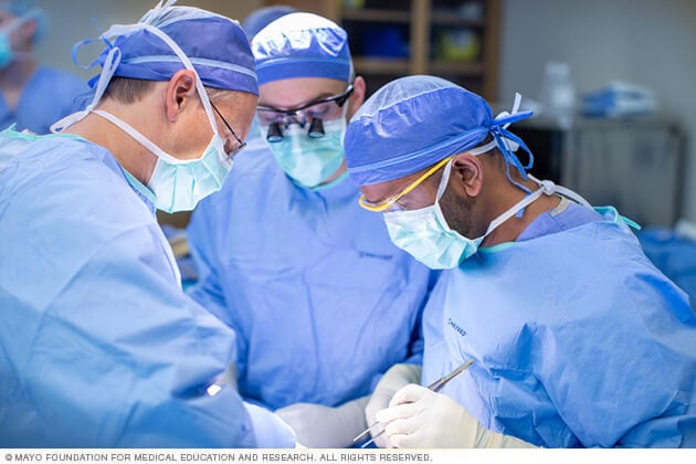 Men's health physicians perform a procedure in surgical scrubs.