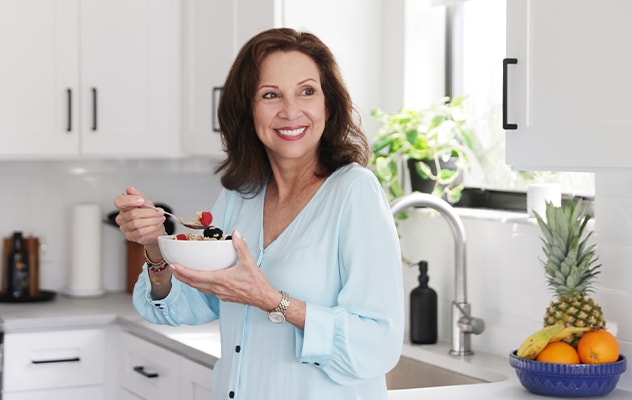 Woman eating a bowl of cereal and fruit