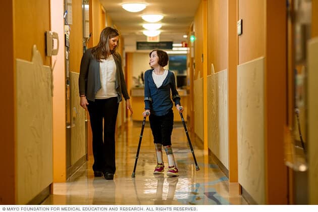 A child using braces and adult walk down a hallway during a CPSB Clinic visit.