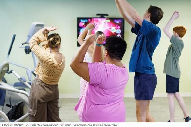 A group of young people dance during a group therapy session.