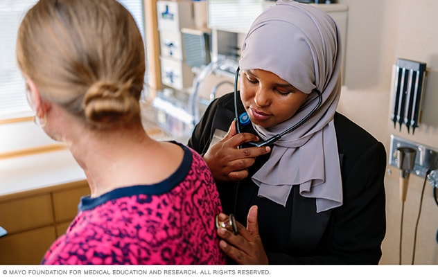 A doctor uses a stethoscope to listen to a patient’s lungs.