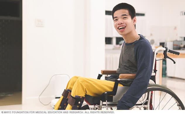 A young man in a wheelchair smiles